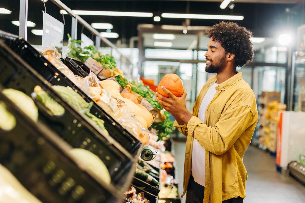 Ein Mann steht beim Einkaufen vor Gemüseregalen