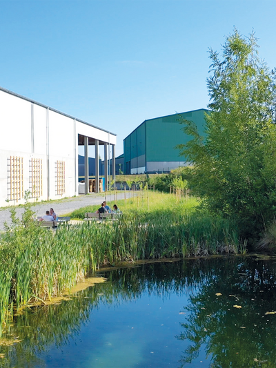 Foto des Betriebsgeländes mit Teich und Sitzmöglichkeiten für Mitarbeiter