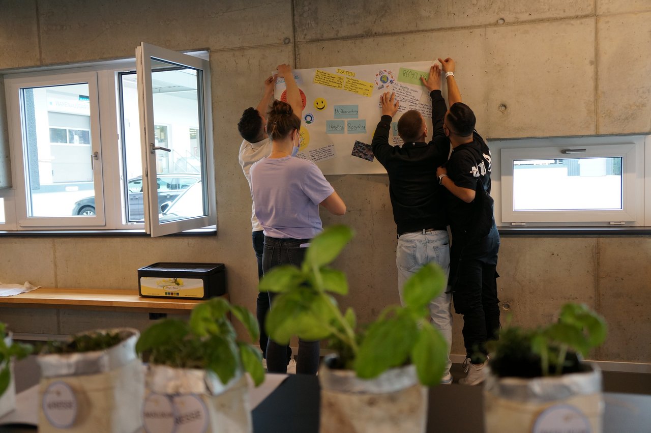 Azubis hängen Plakat mit Notizzetteln auf