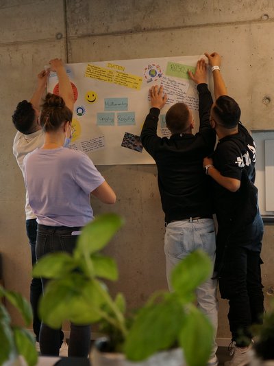 Azubis hängen Plakat mit Notizzetteln auf