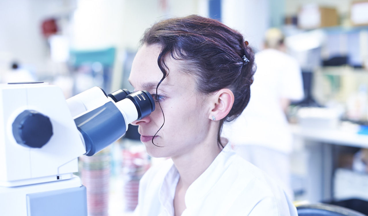 Eine Frau schaut durch ein Mikroskop