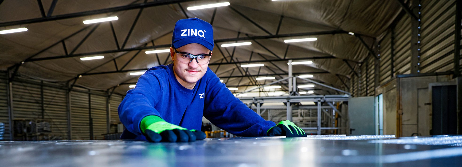 Foto von ZINQ-Mitarbeiter, der über eine Stahloberfläche streicht